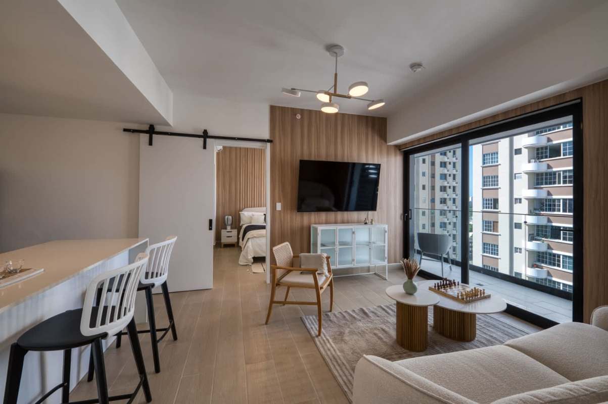 Open-plan modern living room and kitchen with balcony offering city and water views in PH Mantra Punta Pacífica