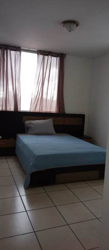Minimalist bedroom with tile floors, large window, blue bedding at PH Vía España Panama