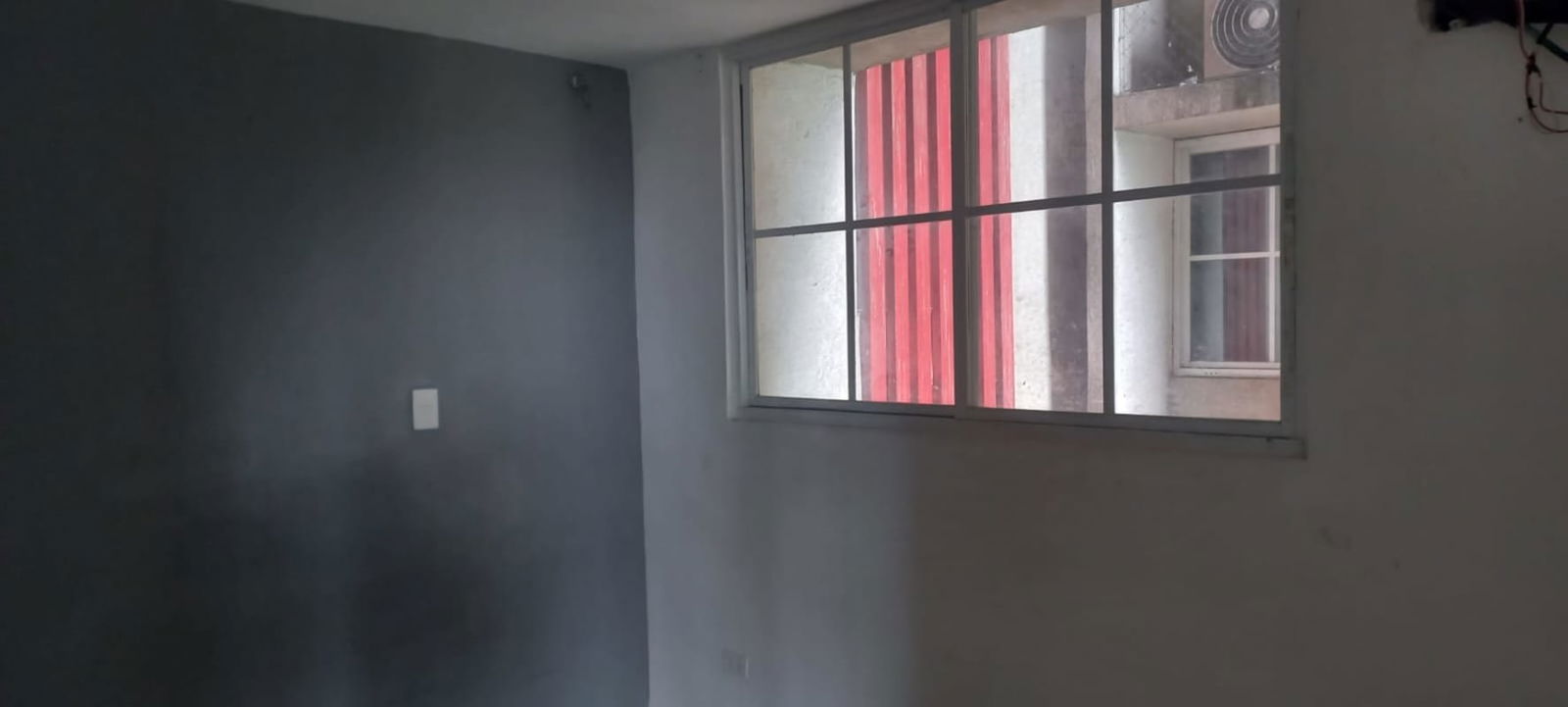 Bedroom with large window and view of adjacent building facade in PH Río de Oro Panama