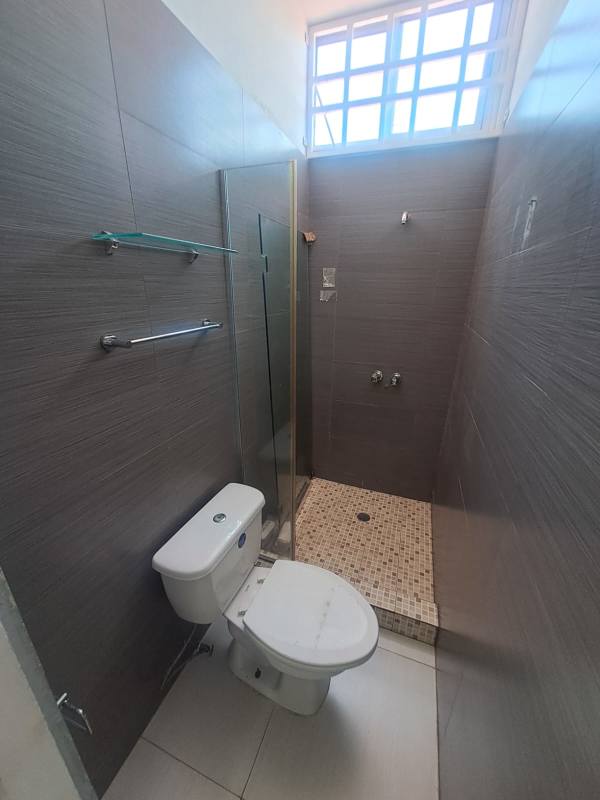 Small bathroom in commercial space with walk-in shower glass partition gray tiles San Francisco Panama