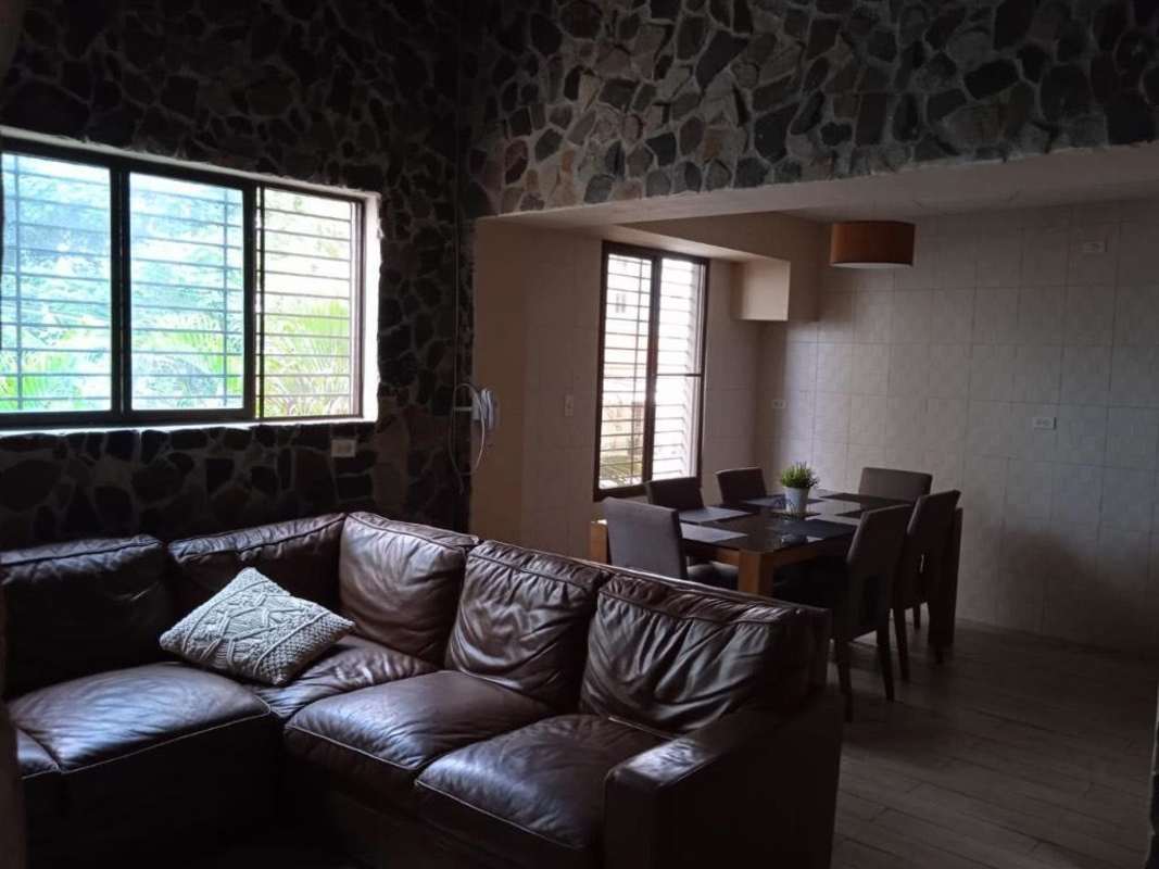 Living and dining room with stone accent wall, wood floor, large windows PH La Cresta Bella Vista Panama City