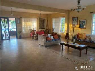 Covered patio with wicker seating, colorful decor, garden view at luxury Playa Blanca villa Panama
