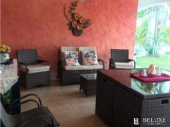 Bright sunroom enclosed with large windows, rattan furniture at Playa Blanca villa Panama