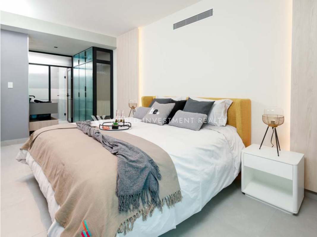 Modern bedroom with yellow bed, ensuite bathroom in Uptown Bella Vista condo Panama City