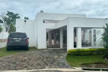 Minimalist white house with flat roof, large windows, driveway and green lawn at Ibiza Residences Río Hato