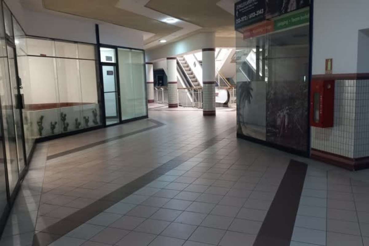 Commercial hallway with glass storefronts and escalator inside Plaza Concordia shopping center Panama