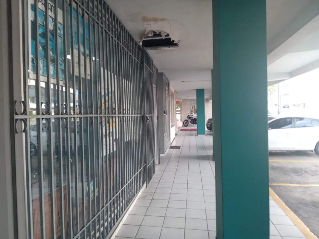 Commercial strip plaza with storefronts, metal gating, parking access in El Dorado Panama