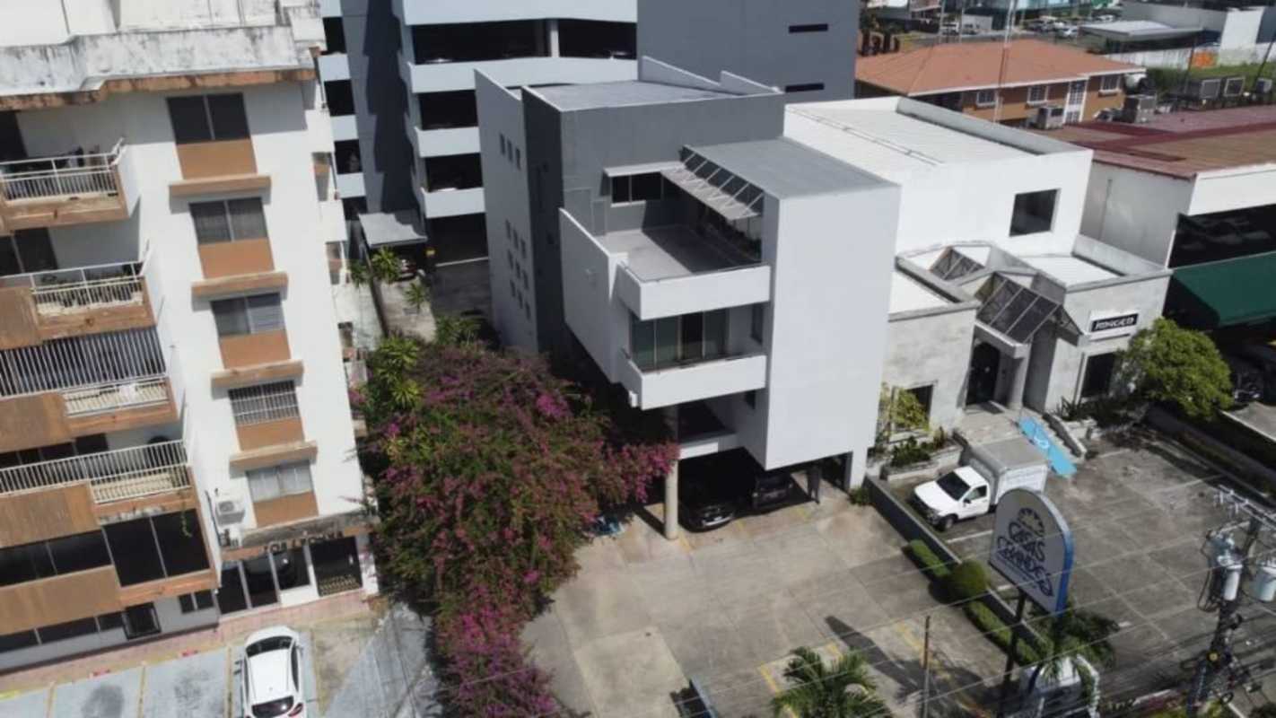 Aerial image of modern commercial building with adjacent parking and city skyline in Panama City