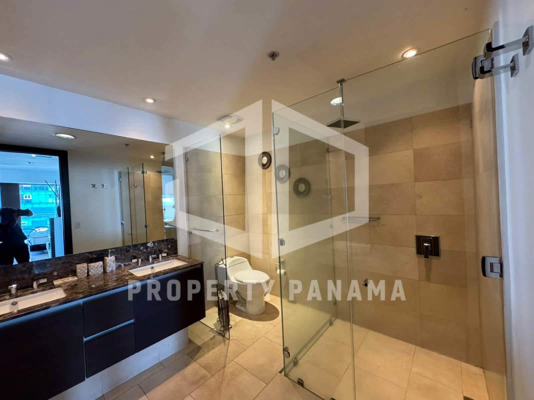 Spacious modern bathroom with dual sink vanity, glass-enclosed shower and marble accents at The Ocean Club Panama