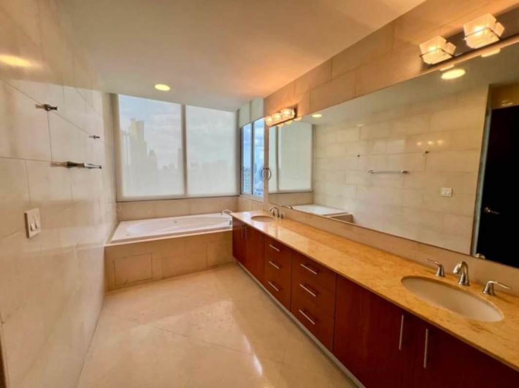 Modern luxury bathroom featuring marble countertops, bathtub, double vanity with city views in The Point Tower