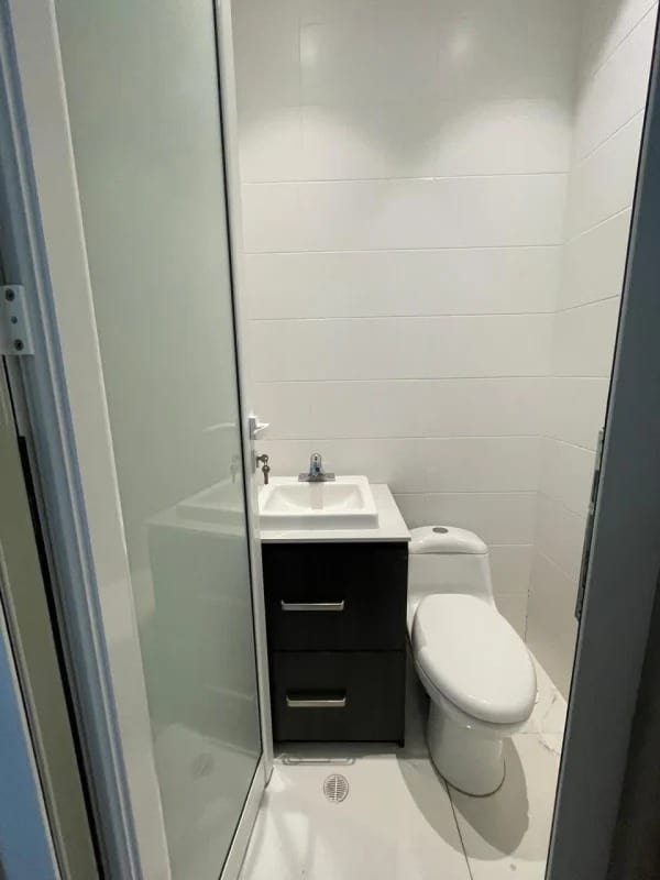 Compact bathroom with white tiles, modern sink cabinet, and toilet in Punta Pacifica Town Center office