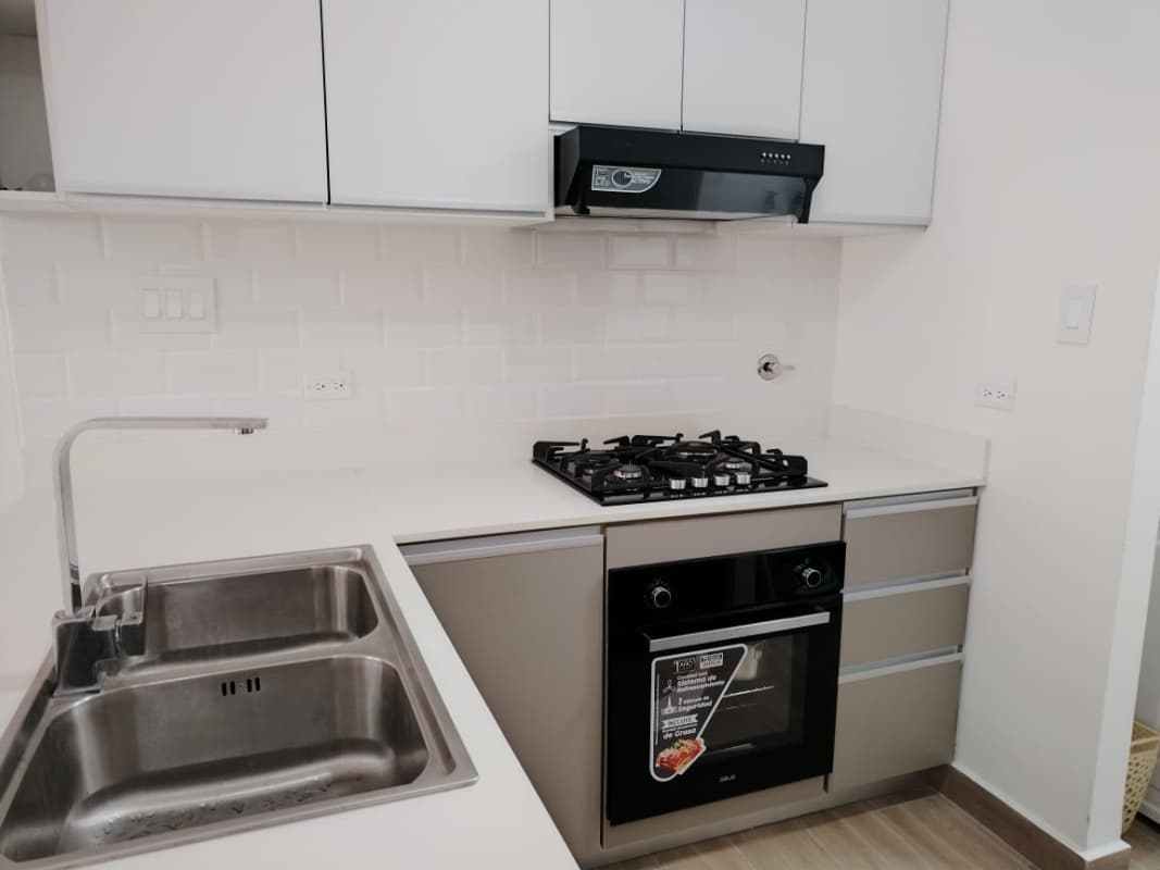 Modern kitchen with white cabinets, gas stove, oven in PH Sky Swiss Panama City