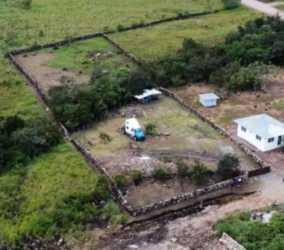 Rural fenced plot with small white house, vehicle, and open yard in Alto Boquete