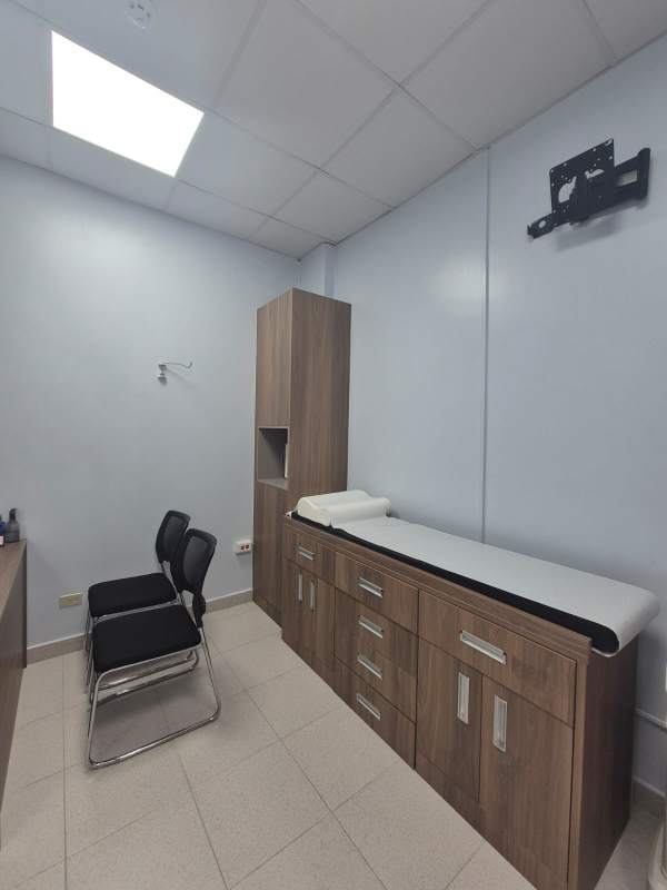 Medical exam room equipped with cabinetry, desk, tiled floor at Pacific Salud Hospital Panama
