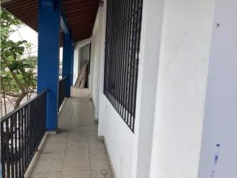 Glass facade commercial space with tiled sidewalk and parked cars in Chitré downtown Panama