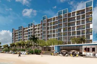 Beachfront multi-story towering condo building with balconies, palm trees PH Surfside Playa Caracol