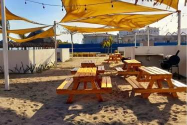 Outdoor shaded picnic zone with BBQ grill and sandy surface at Playa Caracol beach condominium