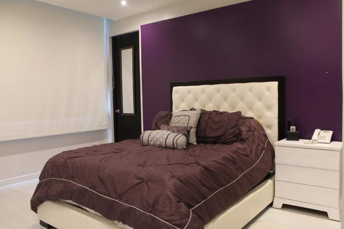 Bedroom with purple accent wall, tufted headboard, modern decor PH The Point Panama City