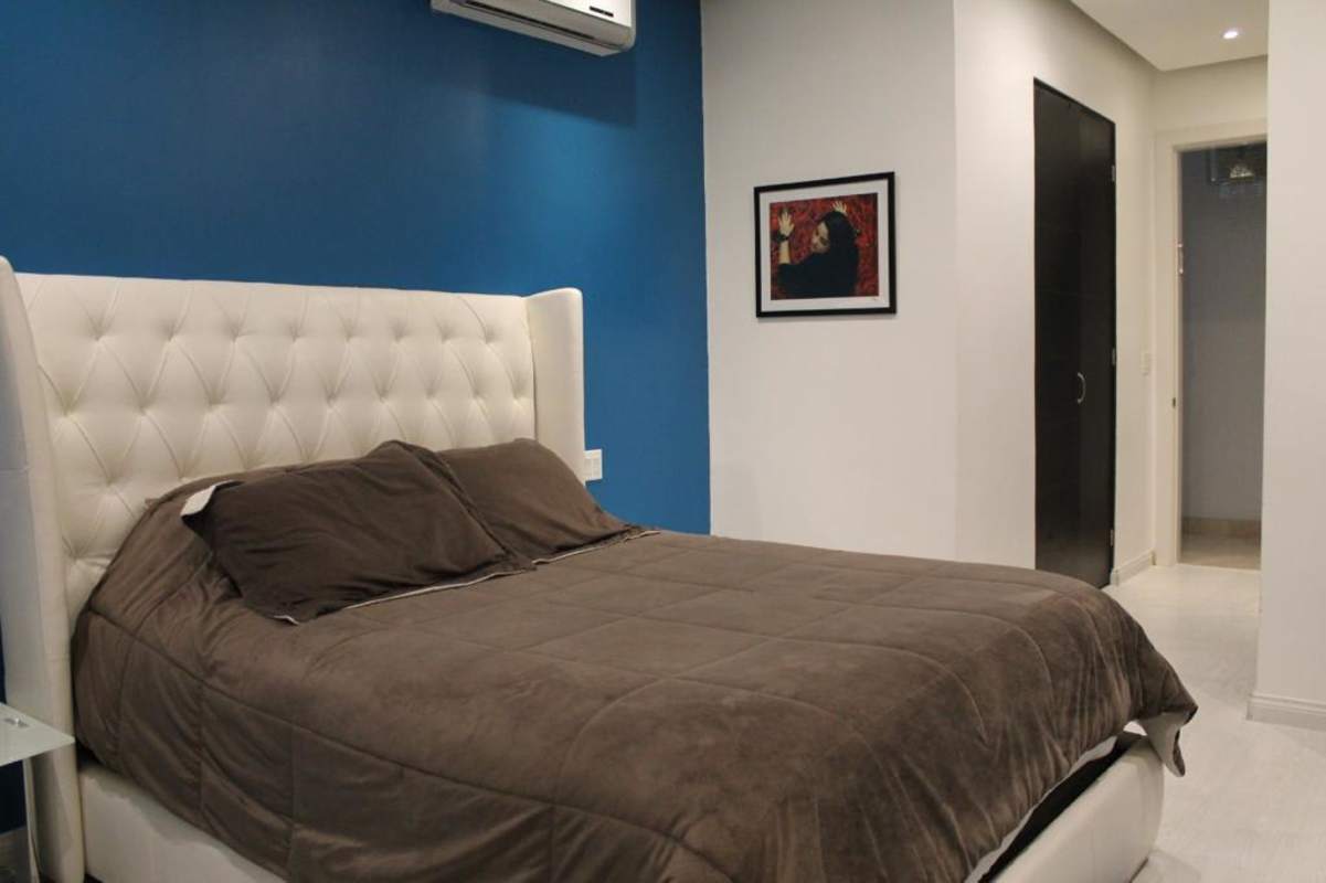Bedroom with blue accent wall, white tufted headboard, recessed lighting, AC PH The Point Panama