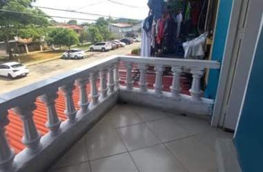 Covered balcony with white railing, street view overlooking residential neighborhood in Arraiján Panama