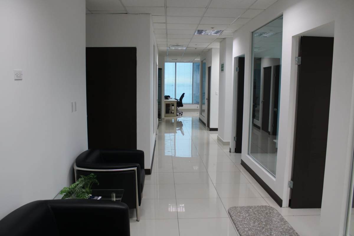 Bright office hallway with glass partitions and black chairs in Ocean Business Plaza Panama City