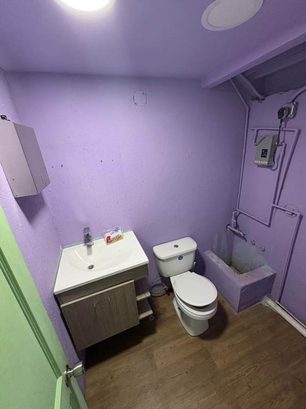 Lavender wall bathroom with toilet and sink inside Plaza SF69 commercial store Panama City.