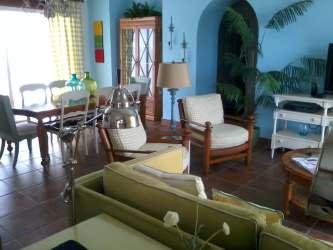 Dining area with wood table adjoining bright living room beachfront apartment Panama