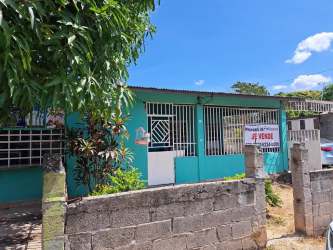 Single-story teal house with security bars and fenced yard for sale Rio Hato