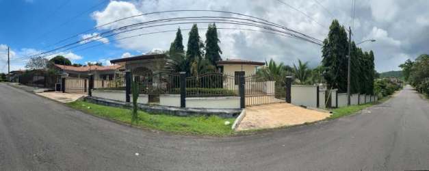 Gated corner lot house with tall trees, metal fencing and concrete driveway in Chiriquí Panama