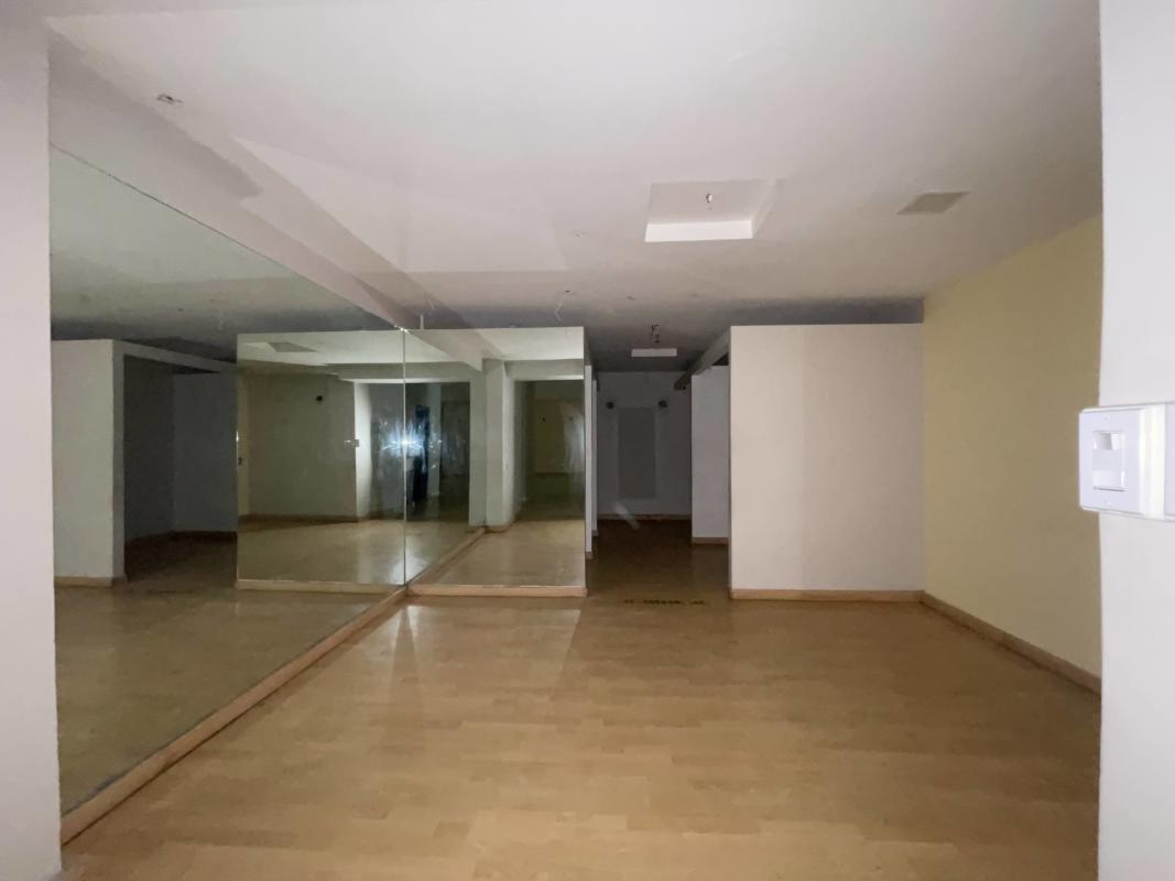 Open multipurpose room with wall mirror and wood flooring at commercial plaza in Panama City