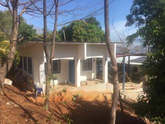 Furnished guest eco cabin with blue doors shaded porch and jungle surroundings Isla Gobernadora Panama