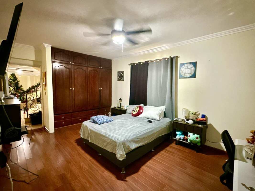 Bedroom featuring wooden wardrobe, fan and wood floors in Las Cumbres villa Panama