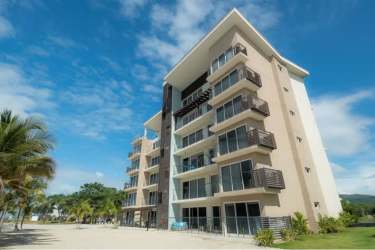 Modern beachfront condo building with balconies and palm landscaping in Playa Caracol Panama