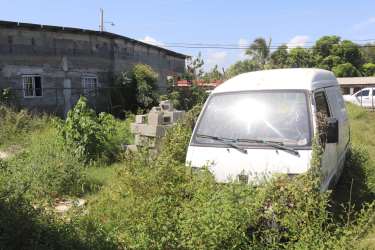 Chain link fenced vacant lot with shade trees Barrio El Rosario Chitré Panama