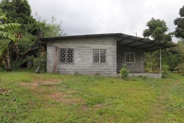 Simple rural house with fenced yard and green vegetation in countryside Boquerón Panama