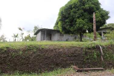 Small unfinished concrete country house with grassy yard, mature tree and elevated terrain in Boquerón Panama