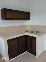 Compact kitchen with beige tile backsplash wooden cabinets L shaped counter rental house Panama Oeste