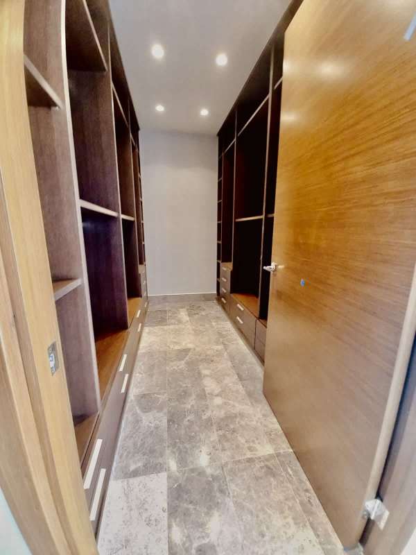 Spacious modern walk-in closet with wood shelves and marble floors at Empire Residences Santa María Panama