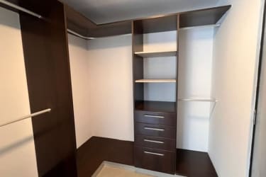 Modern walk-in closet with dark wood shelves and hanging space in Panama Pacifico apartment