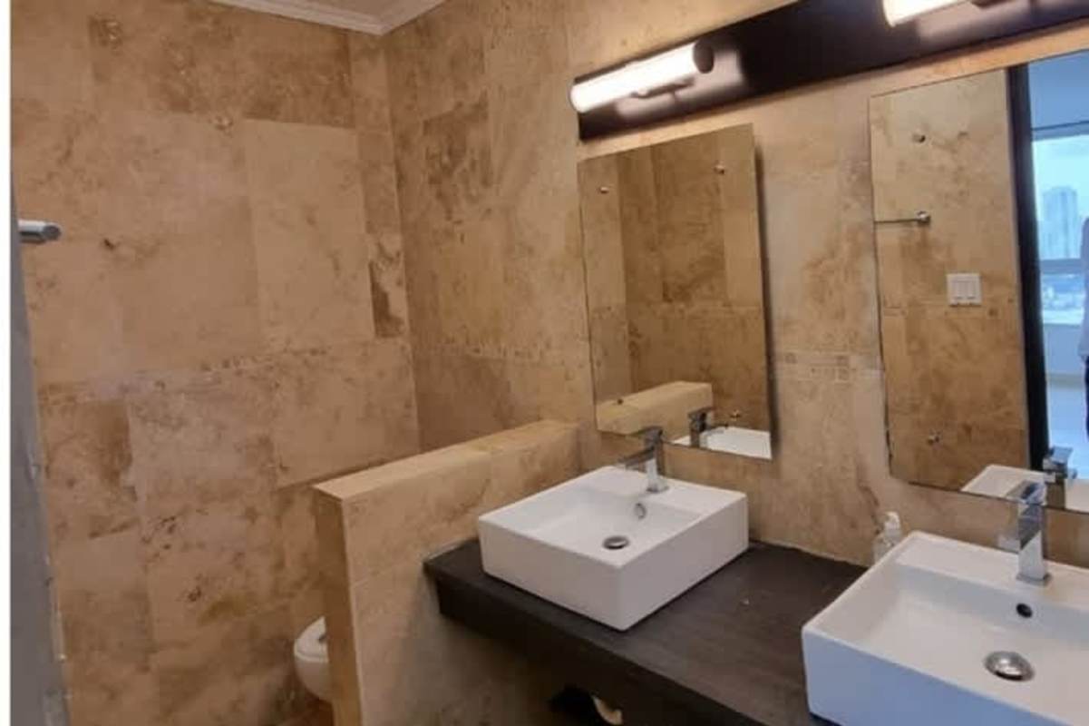 Elegant bathroom with double vessel sinks, marble tile walls, and a large mirror in Pacific Point Tower Panama