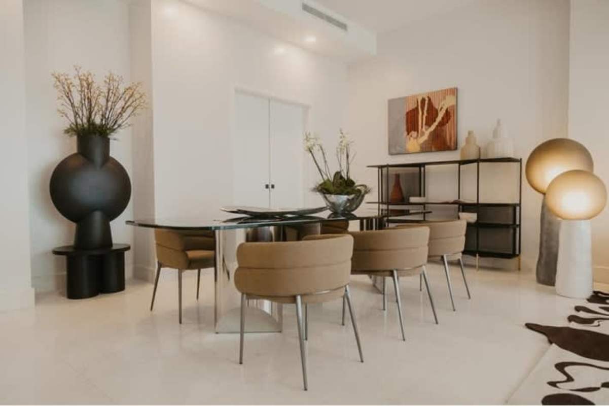 Contemporary dining area with glass table, modern lighting, neutral decor, luxury residence
