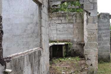 Abandoned unfinished concrete house overgrown grass on lot in Chupampa Panama