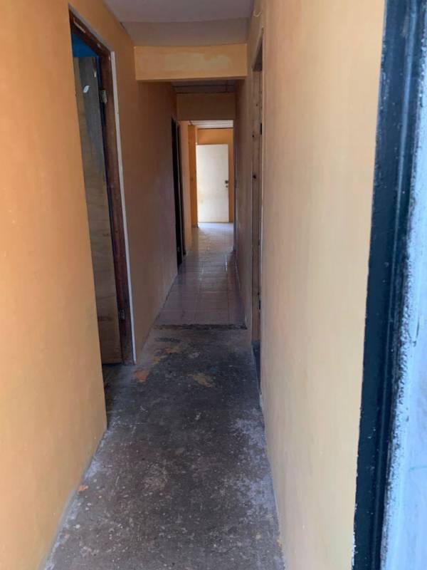 Simple hallway with peach walls unfinished floors leading to house rooms in Trevol 24 de Diciembre