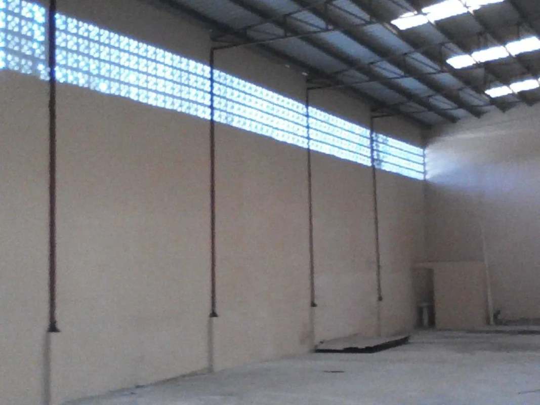 Empty industrial warehouse with ventilation blocks near ceiling, concrete flooring, high metal roof, in El Carmen Panama City