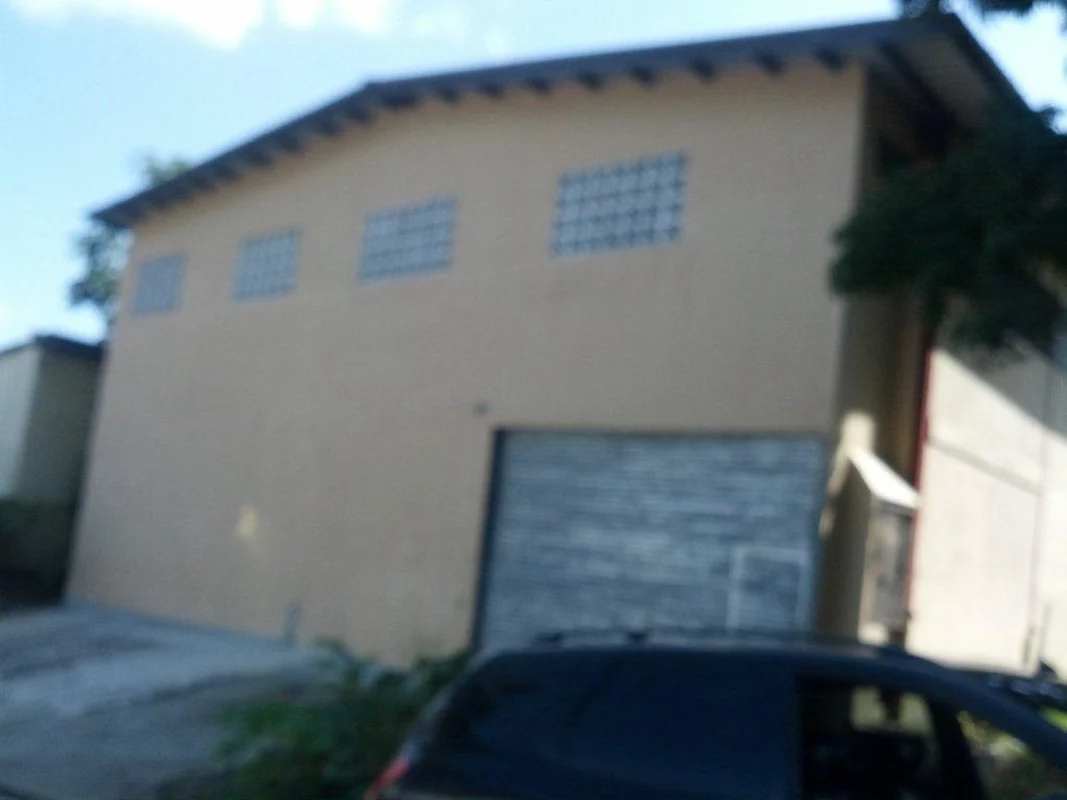 Industrial warehouse interior with metal roof truss, large rolling door, and ventilation glass block in Pueblo Nuevo Panama