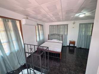 Bedroom in tropical villa featuring light walls, black flooring, minimalist style and AC in Punta Chame