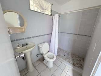 Simple bathroom with tiled walk-in shower and pedestal sink in Panama beach house