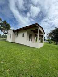 Country home with covered porch surrounded by lush lawn and trees at Hacienda Valle Santa Catalina Panama