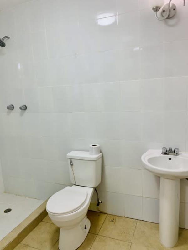 Two-story white building with carport and tropical trees in Clayton Panama