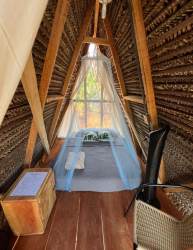 Rustic bedroom with mosquito net and natural wood beams in guest cabin Santa Catalina beachfront Panama
